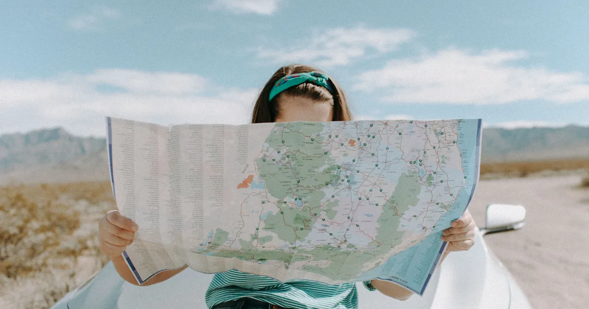 大きな地図を広げ行き先を調べている女性
